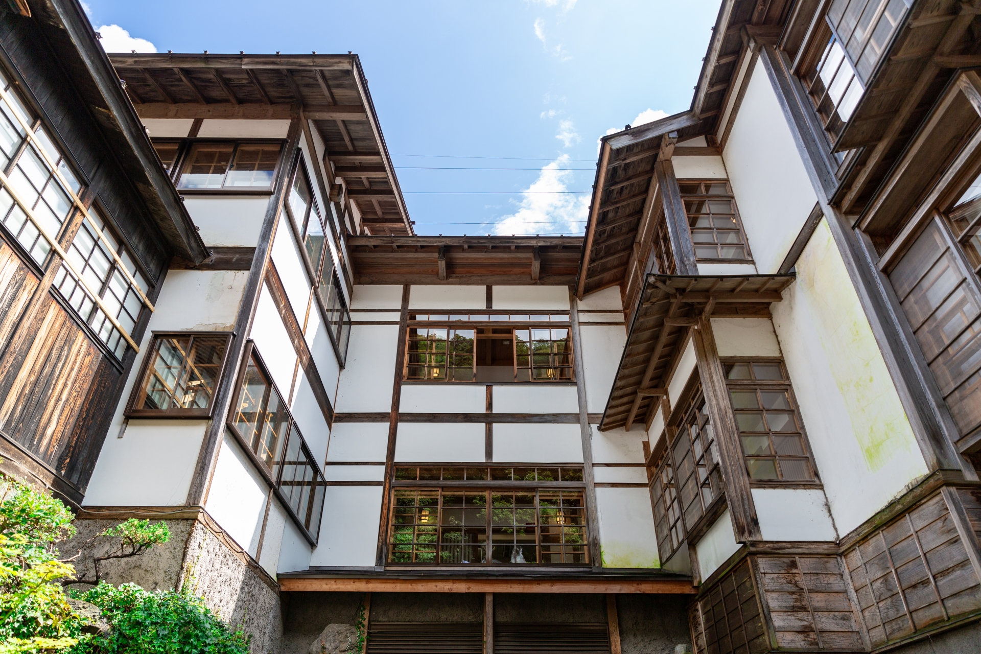 木製の窓と扉を持つ日本の旅館の外観を示す画像。