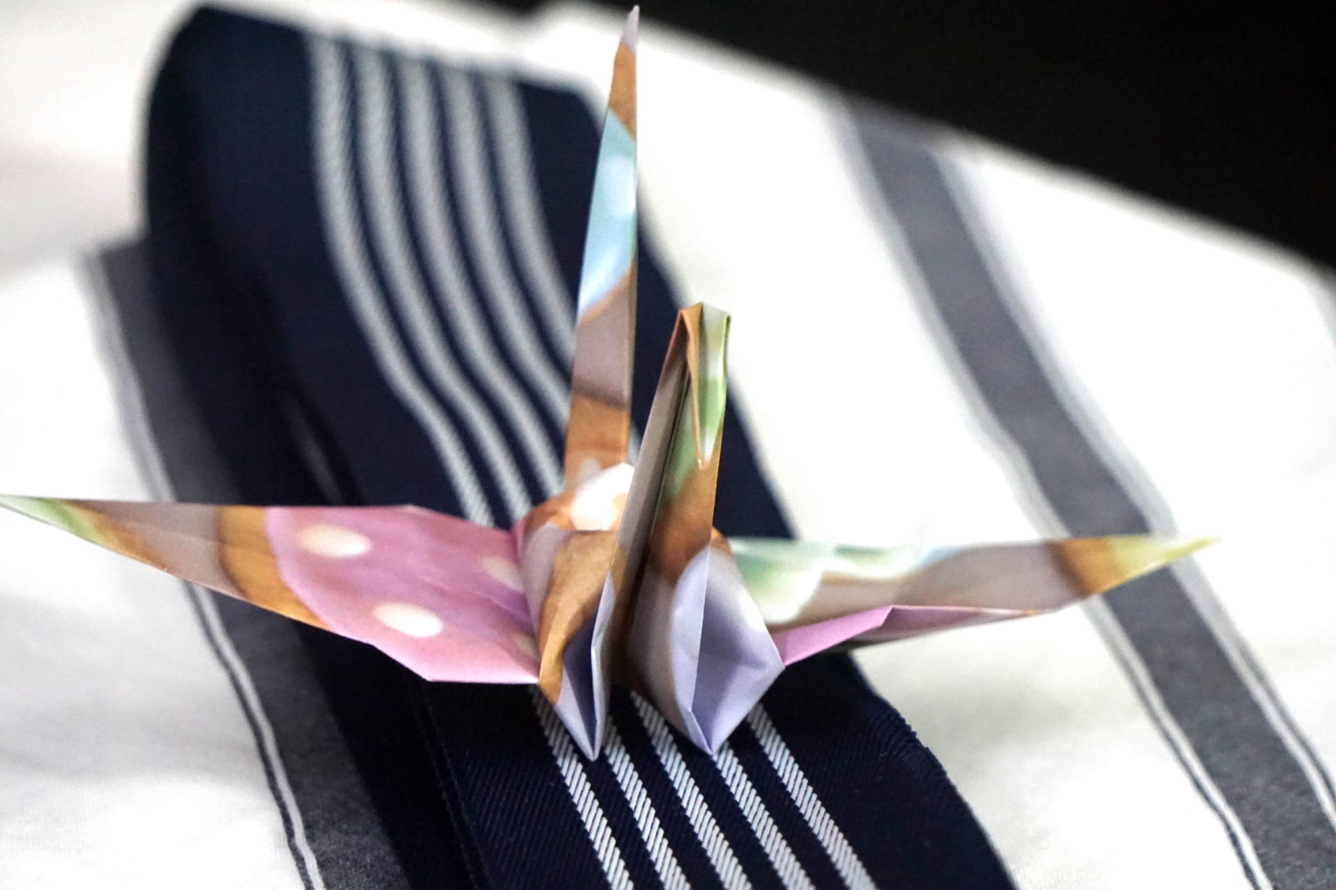 浴衣の上に置かれた折りたたまれた折り紙の鶴の画像。